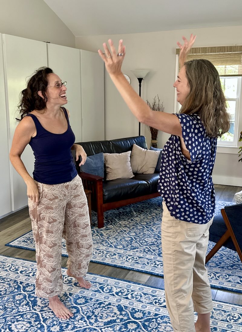 Somatic therapy session. Two people facing each other, one with arms raised.